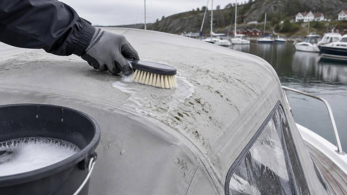 Hånd med hanske børster forsiktig bort mugg fra taket på en grå kalesje