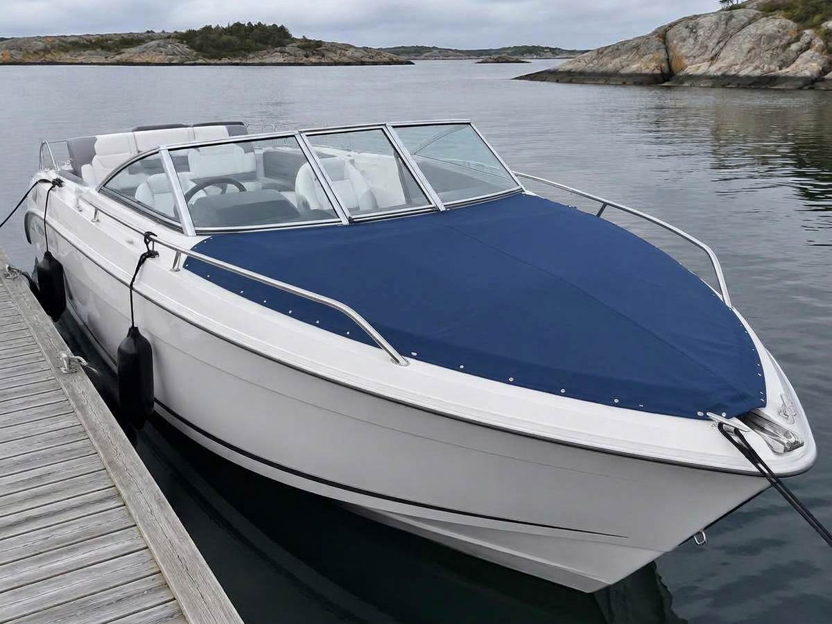 Motorbåt ved brygge med skreddersydd blått baugtrekk over fordekket og åpen cockpit