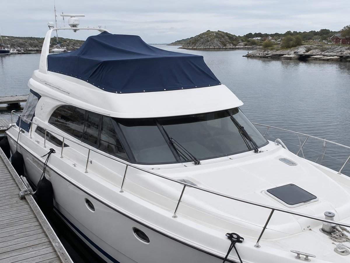 Motorbåt sett fra baugen med skreddersydd marineblått flybridgetrekk over styreplassen på flybridgen